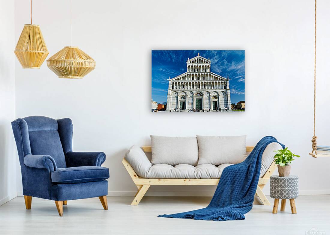 Visitors walk around Pisa Cathedral in Piazza dei Miracoli. The tall structure stands under a blue sky. People enjoy the lively atmosphere. Reproduction