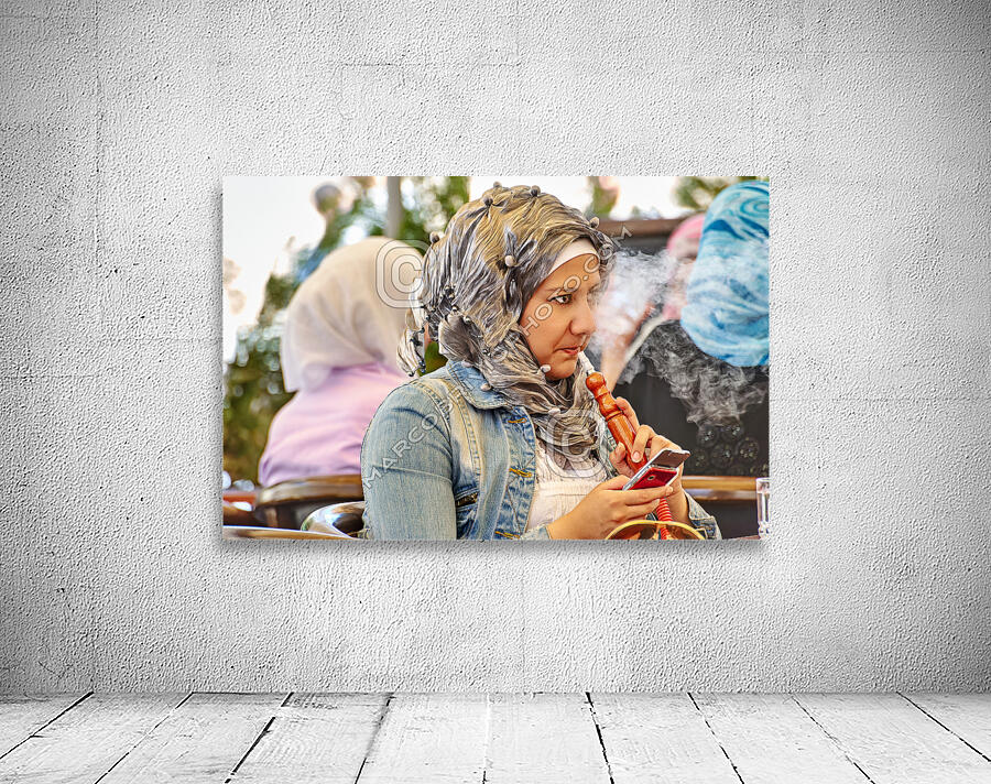 Syria. Aleppo. Girl smoking hookah and looking at her smartphone Wall Preview