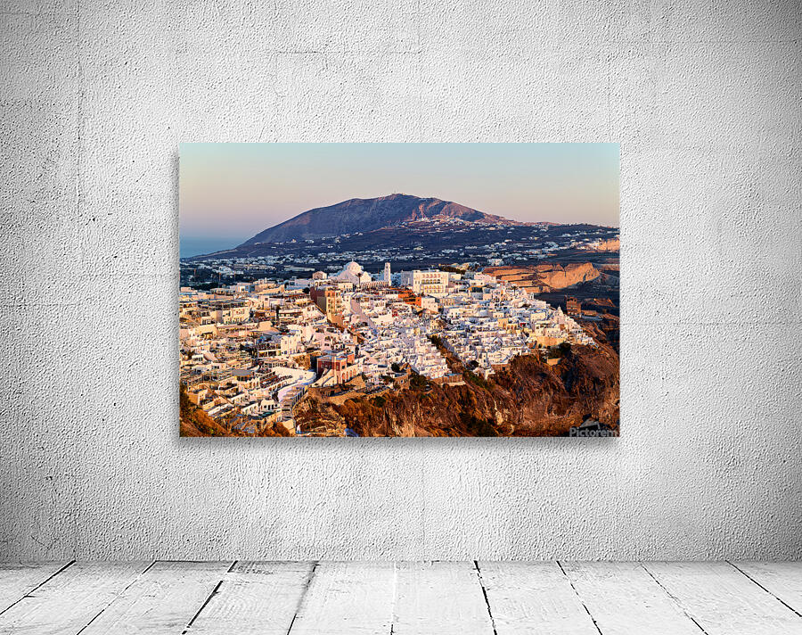 Santorini cliffside town at sunset with mountain backdrop. Wall Preview