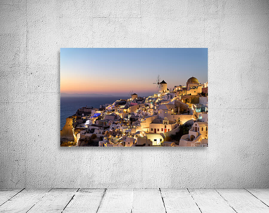 Santorinis Oia village glows at twilight by the sea. Wall Preview