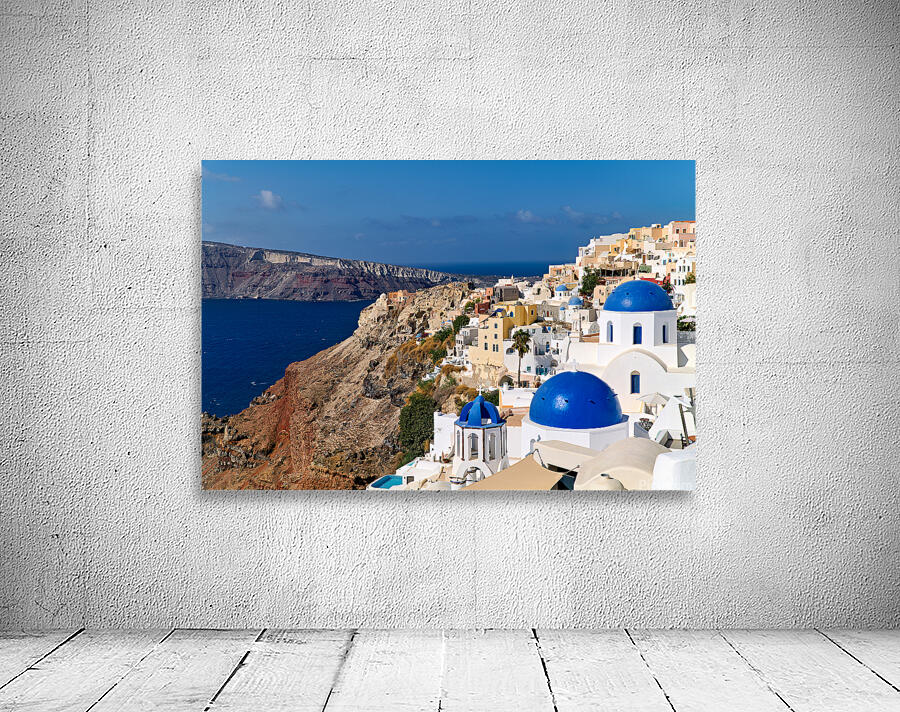 Santorinis iconic white buildings and blue domes overlooking th Wall Preview