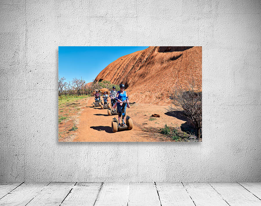 Tourists ride Segways near Uluru in Australia. Wall Preview