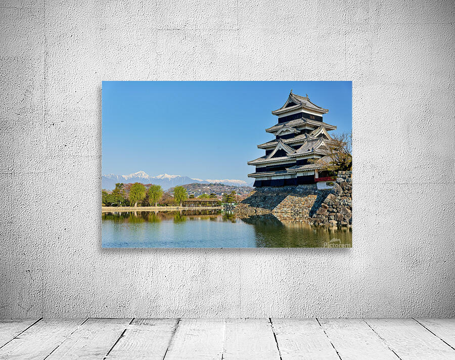 Matsumoto Castle stands beside water with mountains in the dista Wall Preview