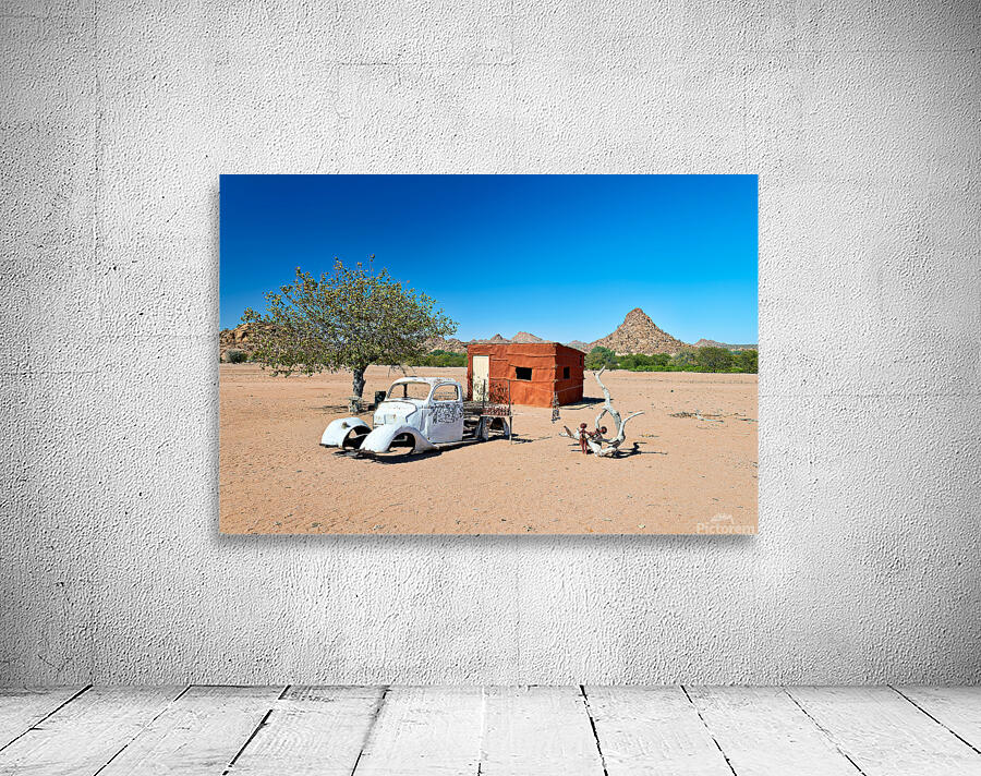 Classic car wreck in Namibias desert landscape near a structure Wall Preview