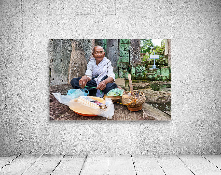 Elderly person selling goods at ancient temple ruins. Wall Preview