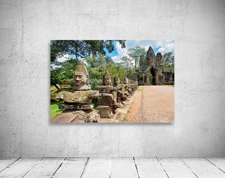 Ancient stone statues line path to Angkor Thom gate. Wall Preview