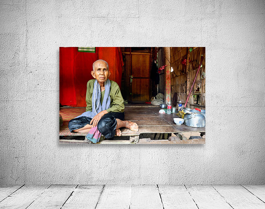 Elderly person sitting on floor in rustic dwelling. Wall Preview