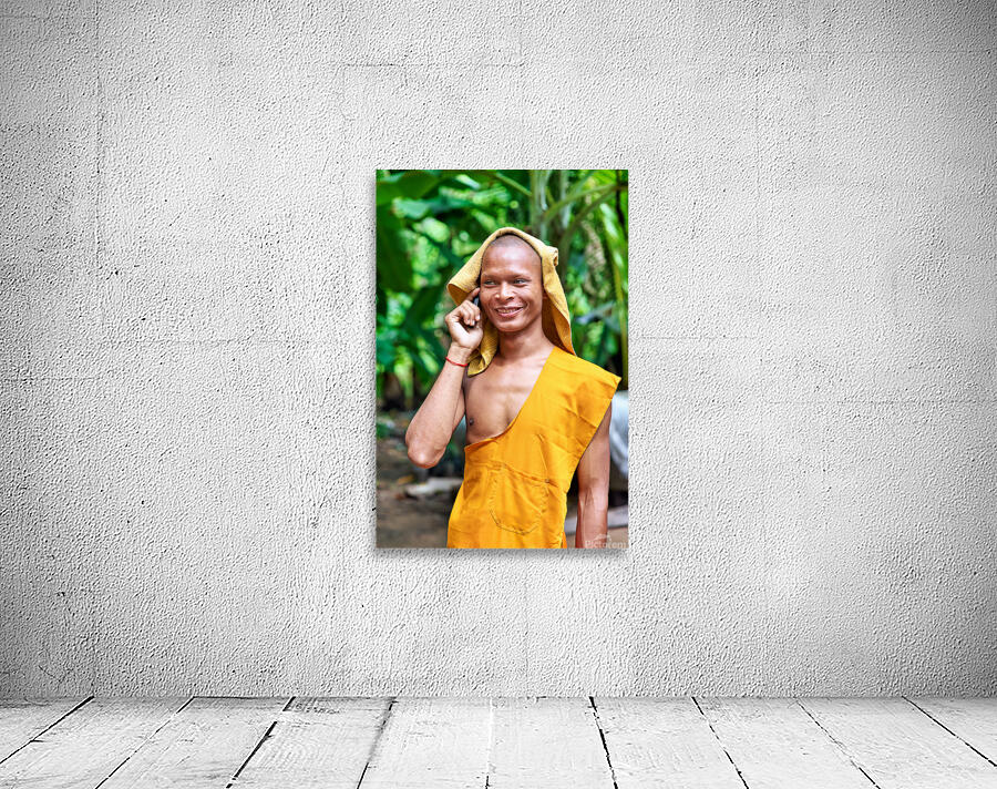 Smiling monk talks on phone with towel on head. Wall Preview