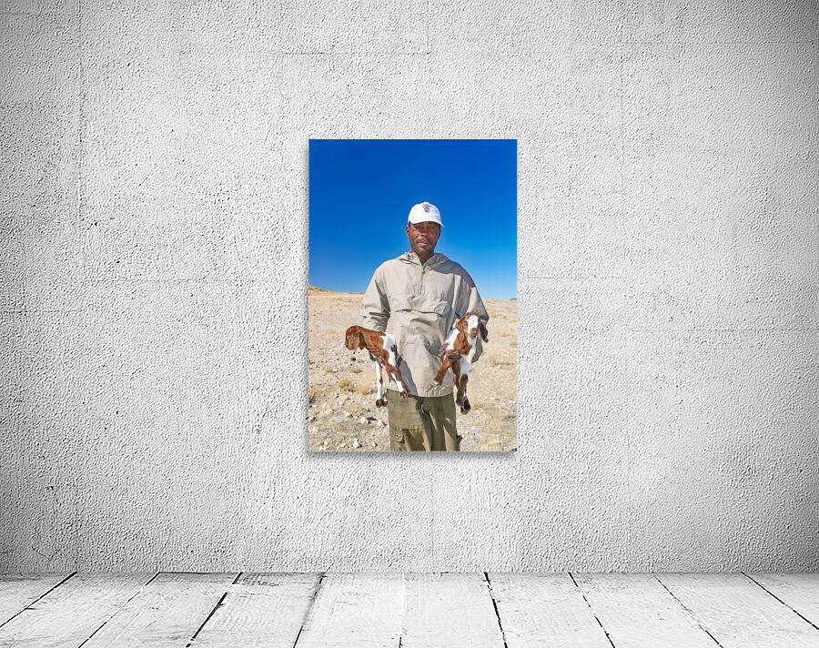 Shepherd holds his young goats in Namibia under bright blue sky Wall Preview