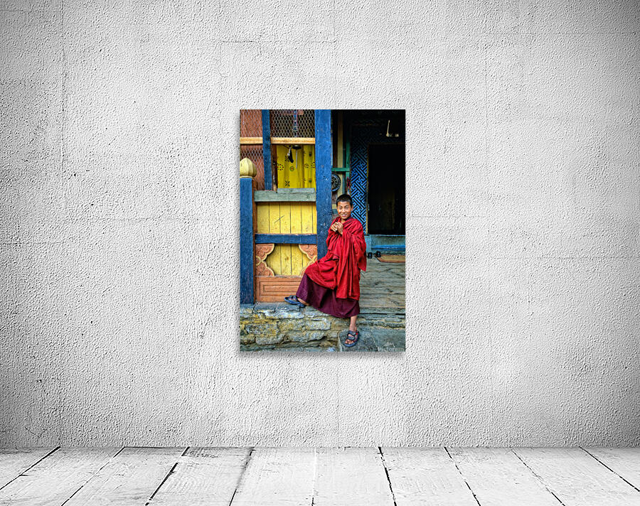 Smiling young monk in red robes at colorful traditional building Wall Preview