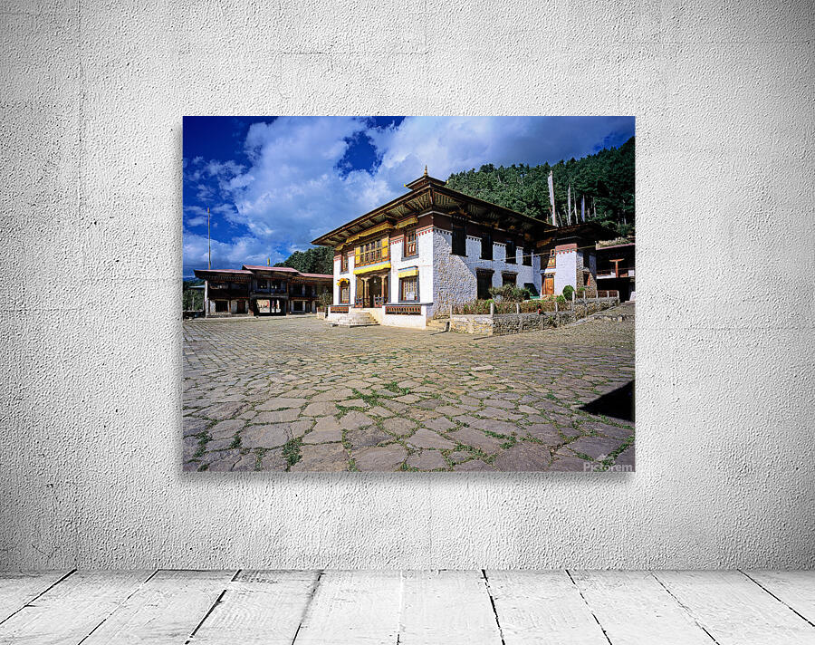 Traditional Bhutanese building with stone courtyard under a clou Wall Preview