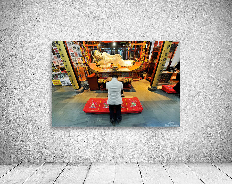 Worshipper kneels before Buddha statue in Shanghai temple Wall Preview