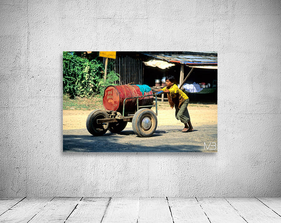 Boy pushes a cart down the street in Myanmar during the day Wall Preview
