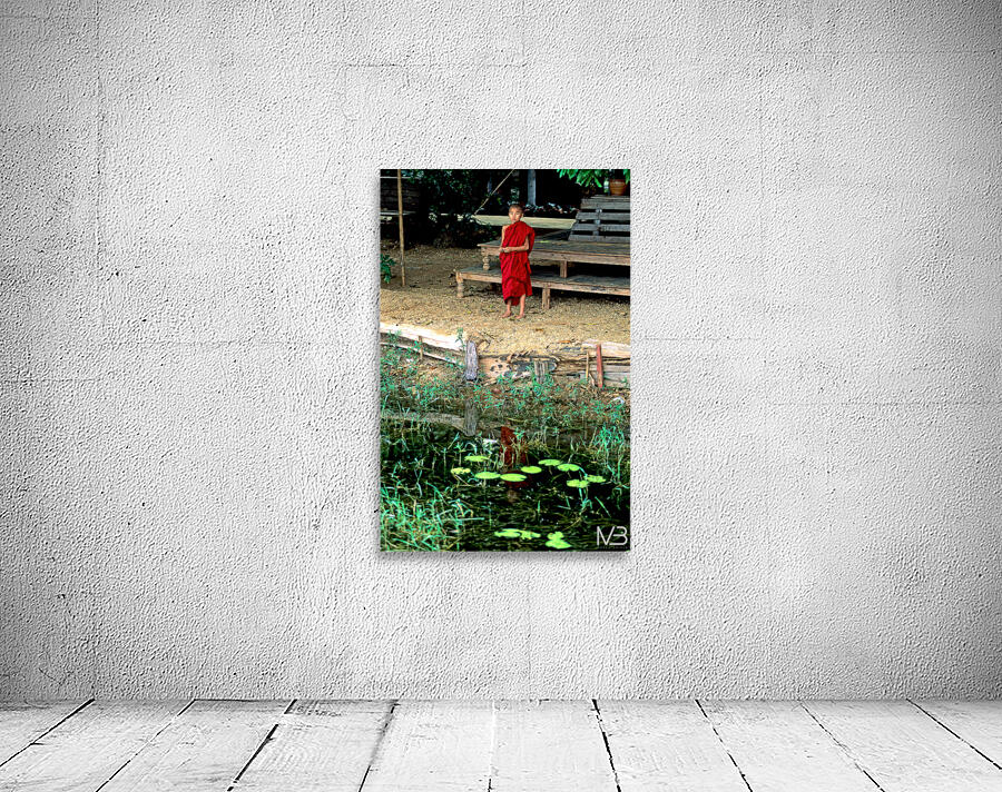 Young monk stands by water in Myanmar during daytime Wall Preview