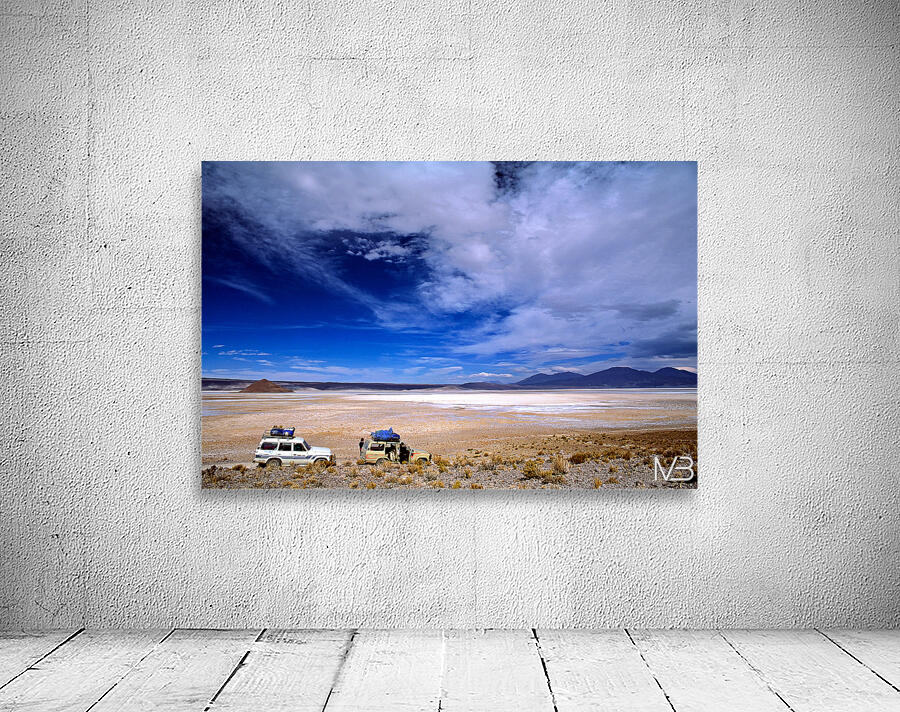 Vehicles traverse a vast arid salt flat landscape. Wall Preview