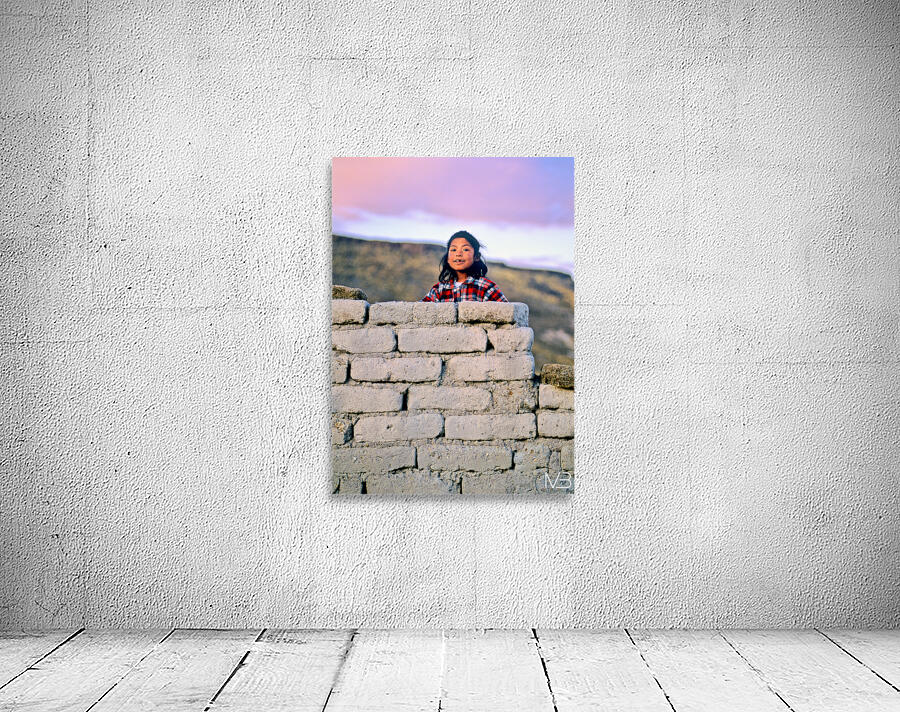 Young girl smiles over stone wall at sunset. Wall Preview