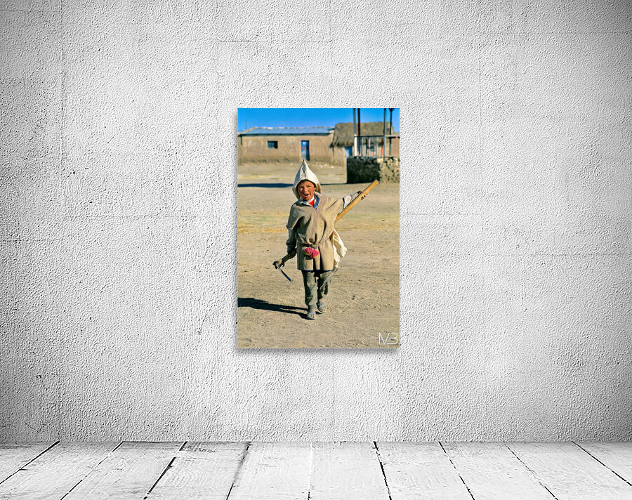 Indigenous boy with tools walks through a dusty village. Wall Preview
