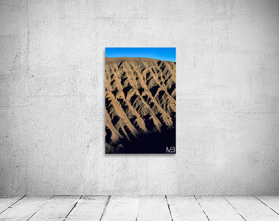 Hiker traverses a dramatic shadowed desert landscape. Wall Preview