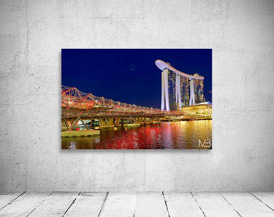 People walk across the Helix Bridge as the Marina Bay Sands Hotel shines at sunset. The sky turns orange and lights reflect in the water. Wall Preview
