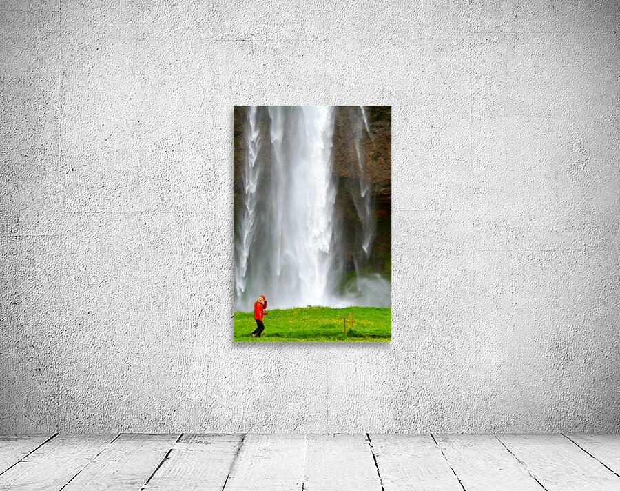 Woman walks near Seljalandsfoss waterfall in Iceland Wall Preview
