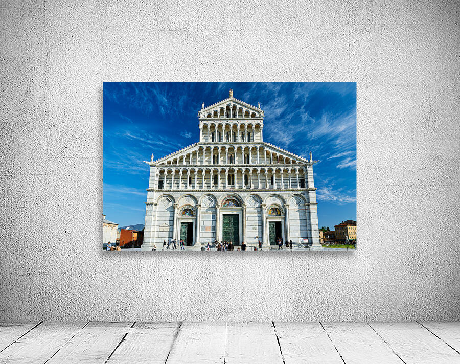 Visitors walk around Pisa Cathedral in Piazza dei Miracoli. The tall structure stands under a blue sky. People enjoy the lively atmosphere. Wall Preview