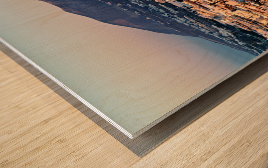 Santorini cliffside town at sunset with mountain backdrop. Wood print