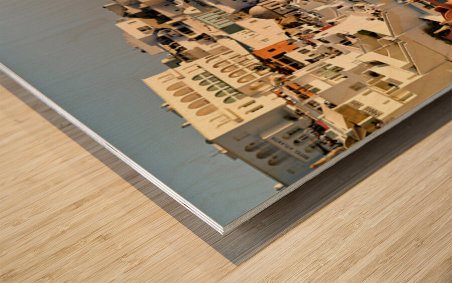 Santorinis white buildings cascade down cliff to the sea. Wood print