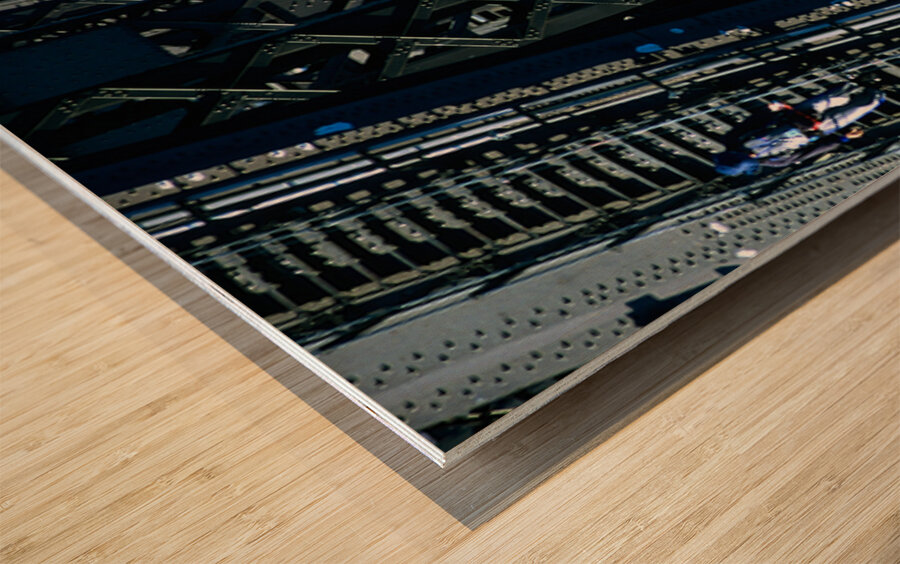 Man walks on bridge with cars below Wood print