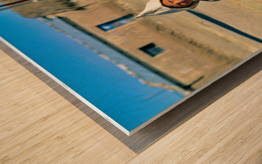 Indigenous boy with tools walks through a dusty village. Wood print
