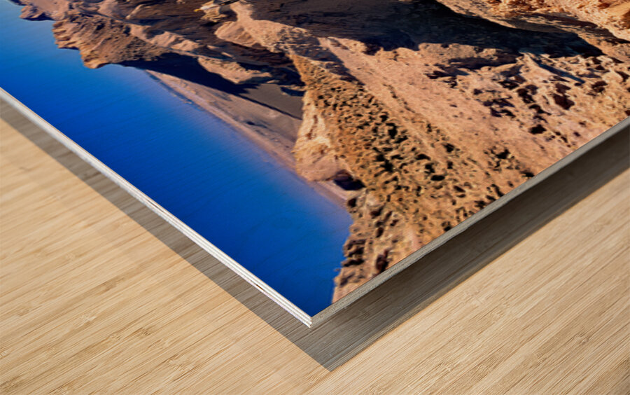 Hikers traverse a vast arid rocky desert landscape. Wood print