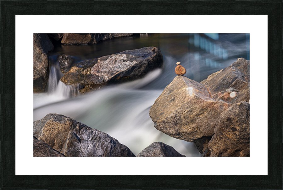 Pebbles balanced on rocks in raging river illustrating resilienc Picture Frame print