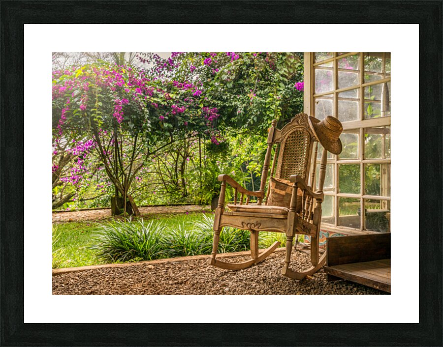 A vintage wooden rocking chair with a straw hat rests on a porch Impression et Cadre photo