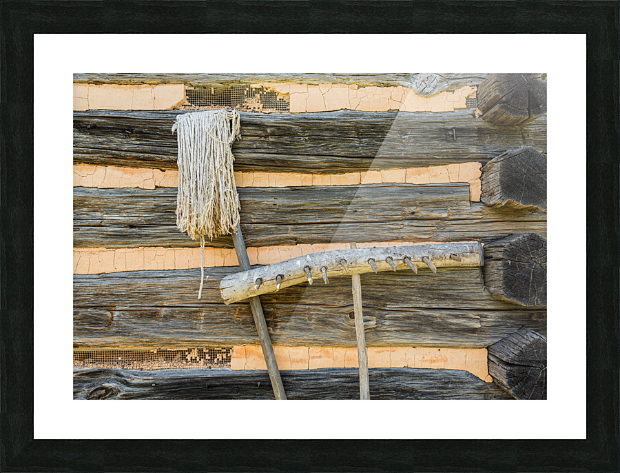 Old rake and mop against log cabin Picture Frame print