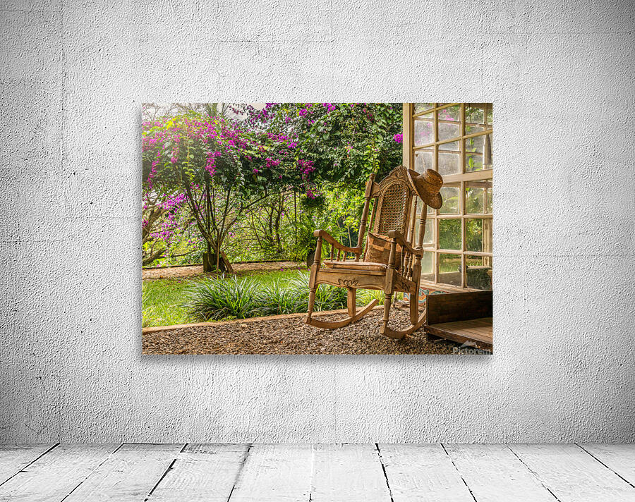 A vintage wooden rocking chair with a straw hat rests on a porch Wall Preview