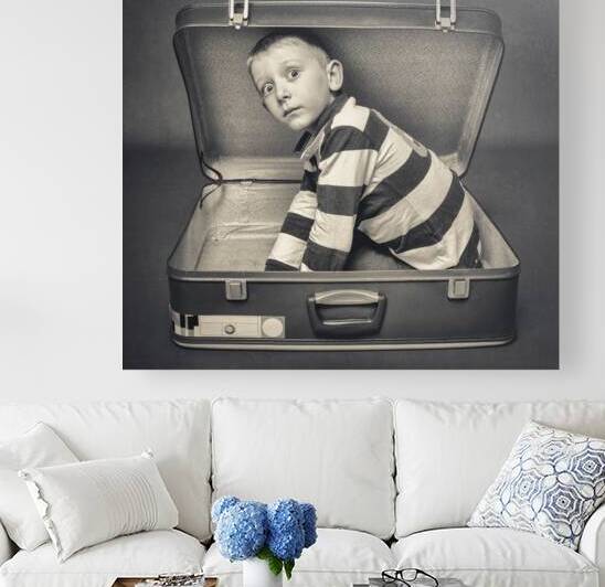 child with astonished expression in a suitcase by Gualtiero Boffi