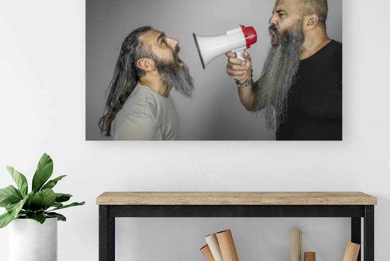 man yells with megaphone to another man by Gualtiero Boffi