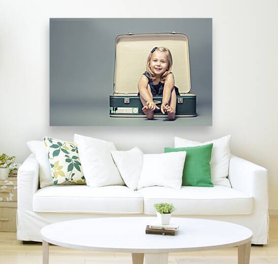 blond girl sitting in a vintage suitcase.  by Gualtiero Boffi