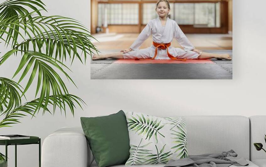 Young girl practicing karate split in dojo by Gualtiero Boffi