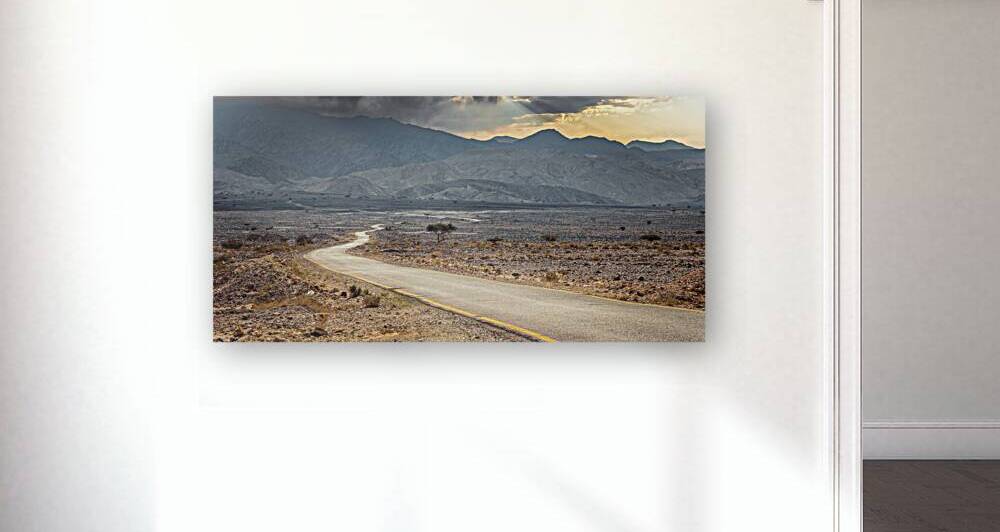 Empty asphalt road winding through a dramatic desert landscape by Gualtiero Boffi