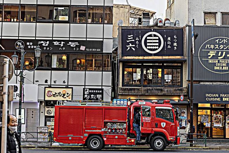 Fire engine parking on a tokyo street with japanese and indian r by Gualtiero Boffi