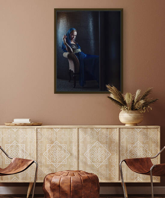Beautiful young blonde woman in with a gyspsy style sitting gracefully in front of a blue ceramic wall looking at the camera in a dark atmosphere by Artmood Visualz