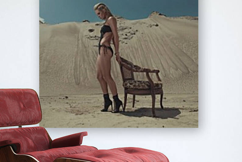 Beautiful young blonde woman in a black swimsuit leaning against a vintage wooden armchair in the desert on a sunny day by Artmood Visualz