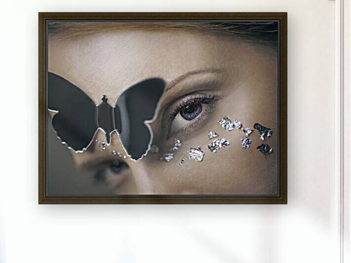 Close up of a blue eyes woman looking at the camera a mirror butterfly on her forehead with silver leaves on her face by Artmood Visualz