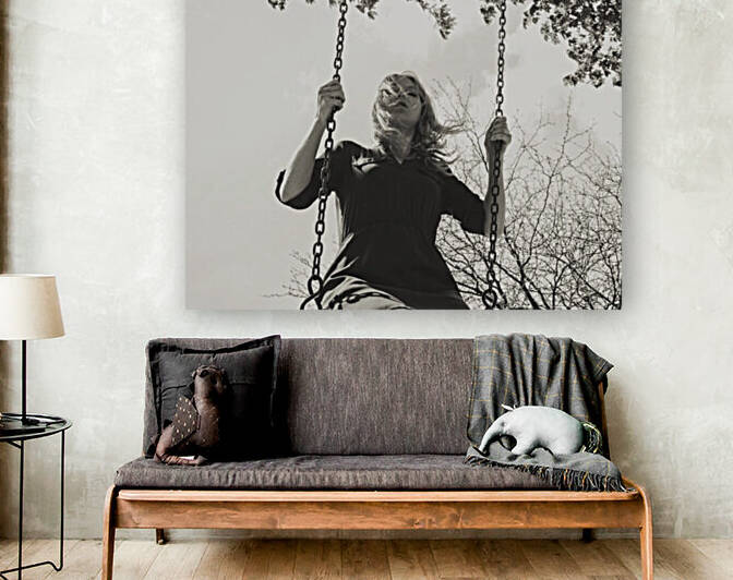 Ground view vintage black and white portrait of a young blonde woman on a swing by a windy day by Artmood Visualz