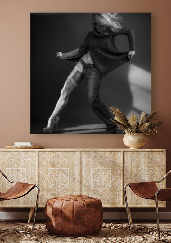 Black and white portrait of a blonde woman wearing both white lace lingerie and a wool sweater with a one-legged jean her hair floating in the wind by Artmood Visualz