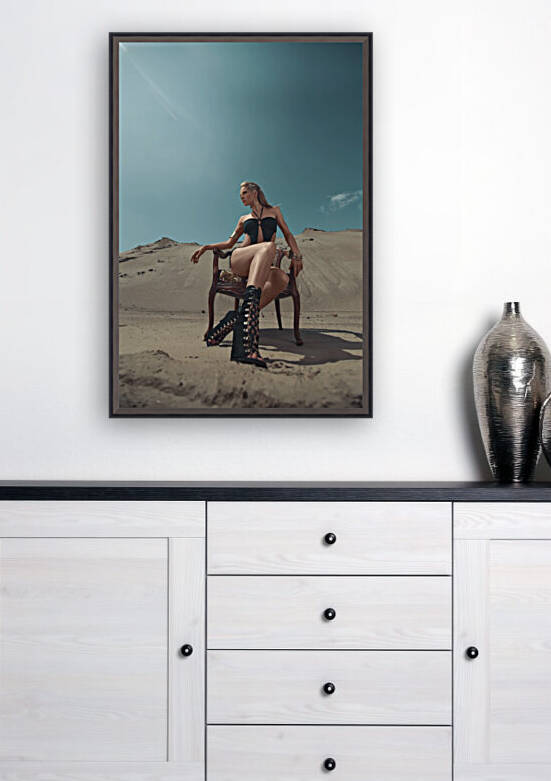 Beautiful young blonde woman in a black swimsuit sitting on a vintage wooden armchair in the desert on a sunny day by Artmood Visualz