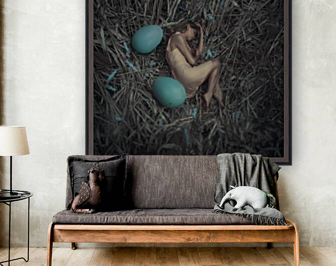 Young blonde woman in a yellow sundress lying down in a nest beside two blue eggs by Artmood Visualz