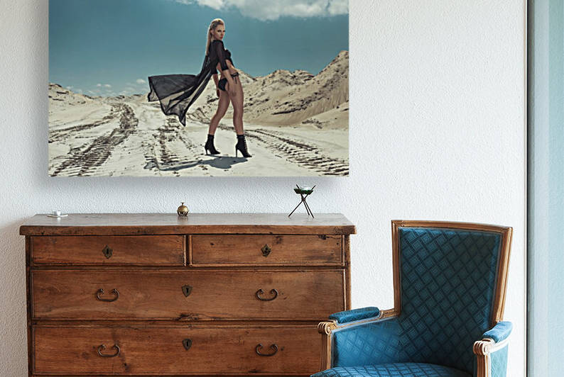 Beautiful young blonde woman in a black swimsuit standing in the sand of a desert on a sunny day turning aroung to look at the camera by Artmood Visualz