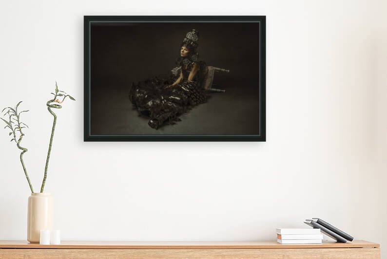 Young woman wearing a headdress an Elizabethan ruff collar and a dress made of archival reels and film sitting on the floor in front of an overturned chair by Artmood Visualz