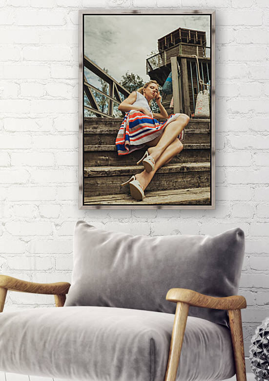 Attractive young blonde woman in a summer dress sitting on stairs in front of a lighthouse by Artmood Visualz